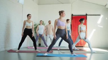 Yoga sınıfı pilates egzersizi. Bir grup sporcu, yoga sağIık meditasyonu için stüdyo sınıfında egzersiz yapıyor. Spor salonunda yoga yapan erkek antrenörler. Spor salonunda esneme hareketleri yapan kadınlar.