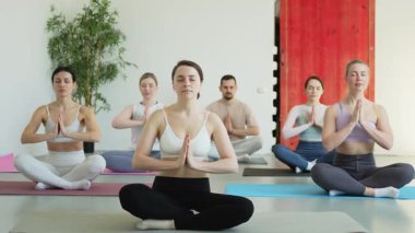 Yoga farkındalığı meditasyonu. Yoga sağlık farkındalığı meditasyonu için stüdyoda egzersiz yapan bir grup sporcu. Nilüfer çiçeğinde oturup yoga yapan erkek kadınlar meditasyon yapıyor.