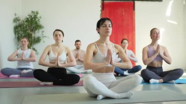 Yoga farkındalığı meditasyonu. Yoga sağlık farkındalığı meditasyonu için stüdyoda egzersiz yapan bir grup sporcu. Nilüfer çiçeğinde oturup yoga yapan erkek kadınlar meditasyon yapıyor.