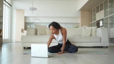 Yoga fitness antrenmanı online. Afrikalı kadın evdeki bilgisayarında online derslerle yoga yapıyor. Yoga minderinde spor yapan bir kız. Kadın kilo vermek için egzersiz yapıyor. Spor uygunluğu