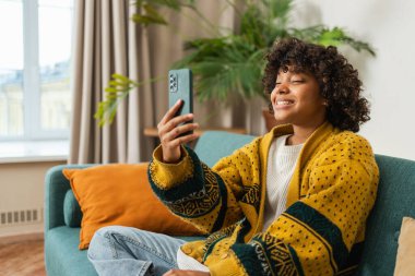African American girl holding smartphone having video chat. Female blogger chatting with best friends in social network. Young woman having virtual meeting online chat video call at home