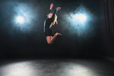 Siyah arka planda dumanla poz veren çağdaş kadın dansçı. Yetişkin kadın sanatçı ifade ile dans ediyor. Modern balerin karanlıkta dans ediyor. Tutku karanlıkta dans eder. Esneklik dengesi