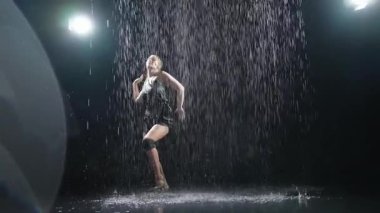 Siyah arka planda yağmur suyunda poz veren çağdaş kadın dansçı. Dişi sanatçı ifade ile dans ediyor. Modern balerin karanlıkta dans ediyor. Tutku karanlıkta dans eder. Esneklik dengesi