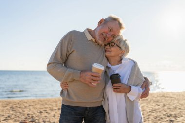 İyi sabahlar. Yetişkin bir çift, kağıt bardak kahveyle yürümekten zevk alıyor. Yaşlı karı dışarı çıkmak için kahve içiyor. Büyükanne büyükbaba birlikte yürümekten hoşlanıyor. Aile âşkı