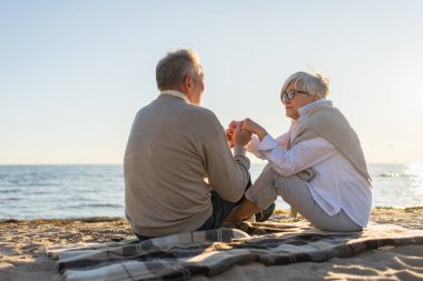 Sahilde oturmuş el ele tutuşan olgun bir çift dışarıda eğleniyor. Yaşlı karı şefkatle el ele tutuşuyor. Büyükannem ve büyükbabam birlikte. Aile âşkı
