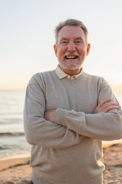 Sahilde kendine güveni tam orta yaşlı bir Avrupalı 'nın açık hava portresi. Yaşlı, olgun bir adam gülümsüyor. Mutlu büyükbaba kameraya bakıyor. Yüz portresi yakın çekim. Mutlu insanlar.