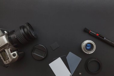 DSR kamera sistemi olan fotoğrafçı işyeri, kamera temizleme seti, siyah masa arka planında lens ve kamera aksesuarı. Hobi seyahat fotoğrafçılık konsepti. Düz görünüm kopyalama alanı