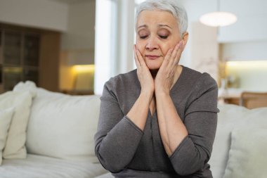 Üzgün, hasta, yalnız, yaşlı bir kadın evde yalnız oturuyor. Mutsuz, olgun bir büyükanne yas tutuyor. Ölümüne kötü haber. Stresli yaşlı kadın yalnızlıktan muzdarip.