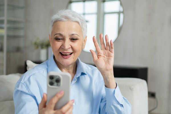 Happy middle aged senior woman talking with smartphone on video call with friends family. Laughing mature old senior lady grandmother having fun talking speaking with grown up children online