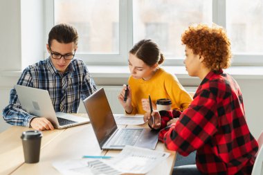 Takım çalışması beyin fırtınası. Çeşitli meslektaşlar birlikte çalışarak mali istatistikleri tartışırlar. Bir grup mutlu modern insan yaratıcı ofiste oturmuş iş tartışıyorlar. Genç profesyonel takım