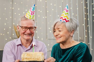 Bir dilek tut. Parti şapkalı son sınıf aile çifti evde birlikte doğum günü kutluyor. Yaşlı kadın doğum günü pastasında yanan mumları üflüyor. Yaşlı adam karısına mutlu yıllar diliyor.