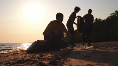 Dünya günü. Gönüllü eylemciler sahil bölgesindeki çöpleri topluyor. Kadınlar ve erkekler okyanus kıyısındaki çöp torbasına plastik çöp koyar. Çevre koruma kıyı bölgesi temizliği