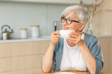 İyi sabahlar. Huzur, evde mutfakta sıcak çay içen yaşlı yaşlı yaşlı kadın büyükanneyi rahatlatıyor. Olgun bir kadın, modern bir evde tek başına sakin bir sabah geçirir. Emeklilik konsepti