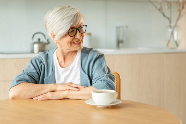 İyi sabahlar. Huzur, evde mutfakta sıcak çay içen yaşlı yaşlı yaşlı kadın büyükanneyi rahatlatıyor. Olgun bir kadın, modern bir evde tek başına sakin bir sabah geçirir. Emeklilik konsepti