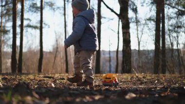 Mutlu bebek dışarıda. Oyuncak arabalı küçük çocuk parkta eğleniyor. Küçük oğlum dışarıda oynarken gülümsüyor. Küçük çocuk doğada dinleniyor. Küçük çocuk yürüyüş yaparken eğleniyor.