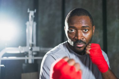 Beden eğitiminde. Afrikalı dövüşçü boksörlere yumruk atmaya hazır koruyucu bandajları kameraya sarar. Güçlü bir adam boks antrenmanına hazırlanıyor.