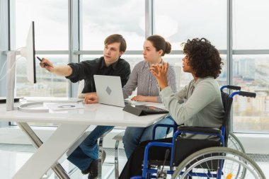 Takım çalışması beyin fırtınası. Çeşitli çok ırklı iş arkadaşları olan kadın engelliler için birlikte çalışıyor. Yaratıcı ofiste oturup iş konuşan bir grup insan. Genç profesyonel takım