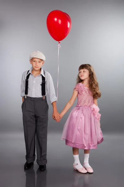 Niedliche Kinder gehen mit einem roten Luftballon — Stockfoto