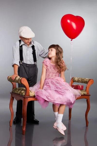 Der Junge schenkt dem Mädchen einen roten Luftballon — Stockfoto