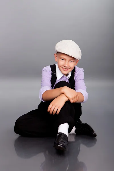 Old fashioned boy sitting on gray background — Stock Photo, Image