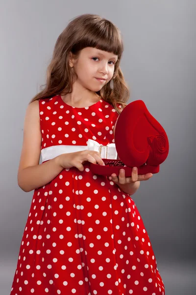 Liten flicka i röd klänning hålla henne närvarande — Stockfoto