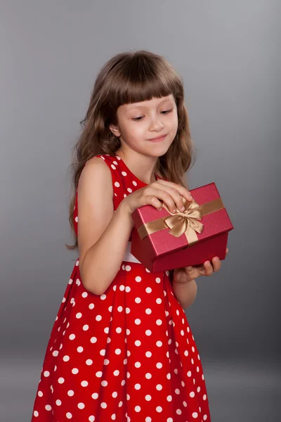 Little girl in red dress holding her present — Stock Photo, Image