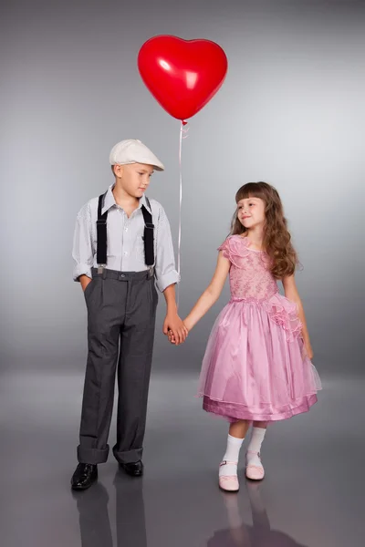 Niedliche Kinder gehen mit einem roten Luftballon — Stockfoto