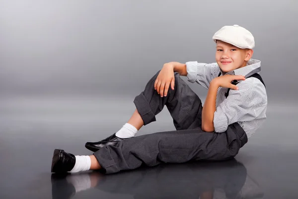 Ντεμοντέ αγόρι καθιστός σε γκρίζο φόντο — Φωτογραφία Αρχείου