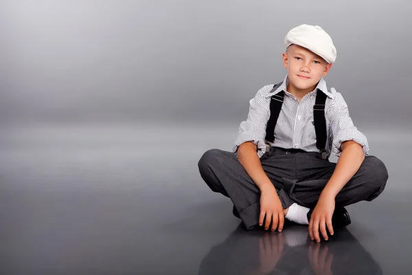 Vecchio ragazzo stile seduto su sfondo grigio — Foto Stock