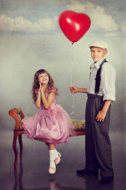 Çocuk kırmızı bir balon kıza verir.