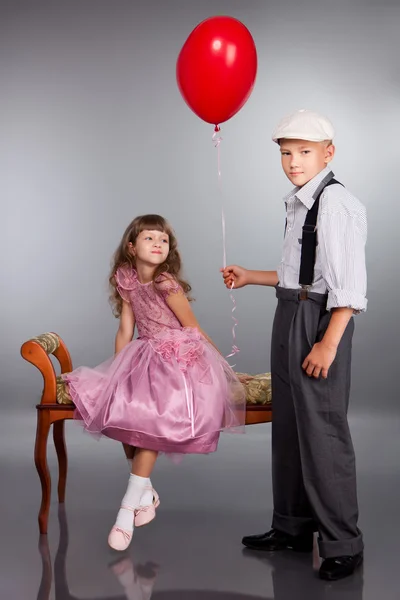 Pojken får en röd ballong till flickan — Stockfoto