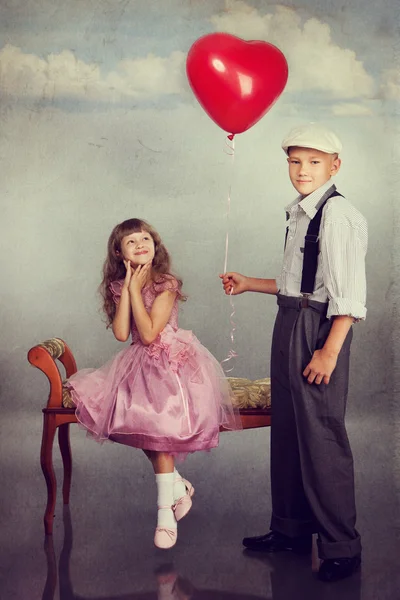 El chico le da un globo rojo a la chica. —  Fotos de Stock