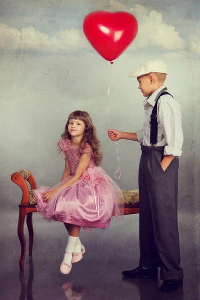 El chico le da un globo rojo a la chica. —  Fotos de Stock