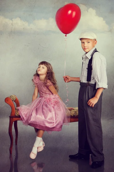 O menino dá um balão vermelho para a menina — Fotografia de Stock