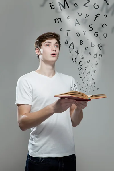 Young man holding a book with alphabet letters — Stock Photo, Image