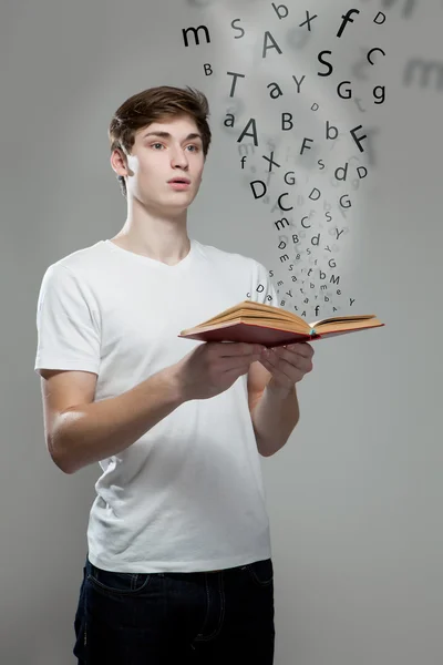 Young man holding a book with alphabet letters — Stock Photo, Image