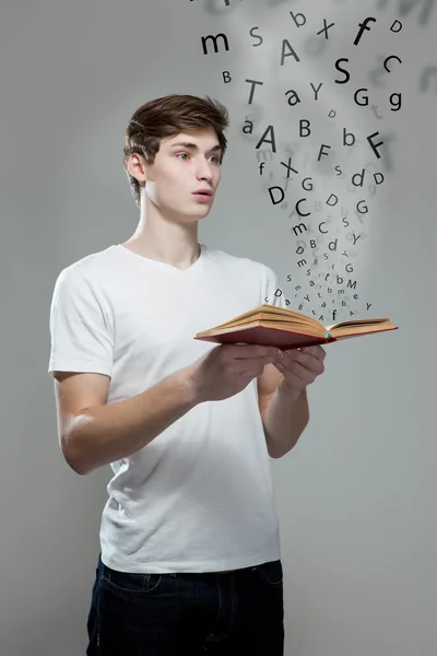 Young man holding a book with alphabet letters — Stock Photo, Image