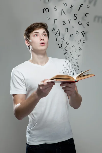 Νεαρός άνδρας κρατά ένα βιβλίο με γράμματα της αλφαβήτου — Φωτογραφία Αρχείου