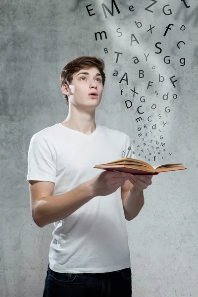 Young man holding a book with alphabet letters — Stock Photo, Image