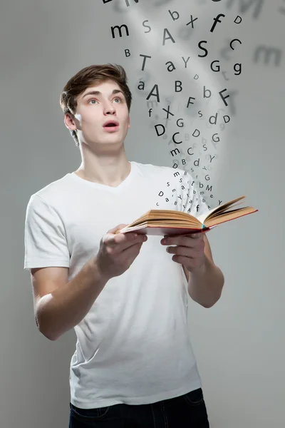 Young man holding a book with alphabet letters — Stock Photo, Image