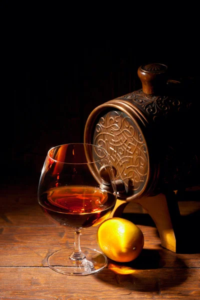 Glas cognac med citron på trä bakgrund — Stockfoto