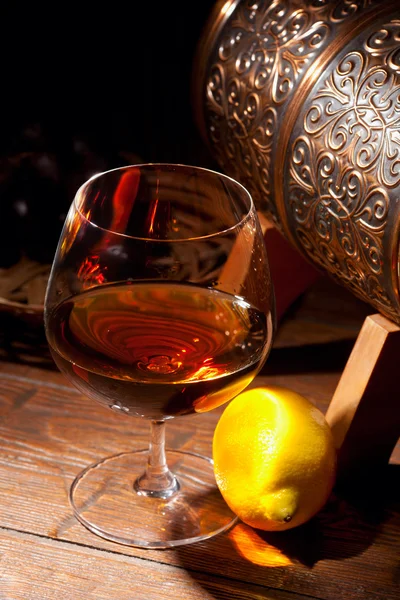 Glas cognac med citron på trä bakgrund — Stockfoto