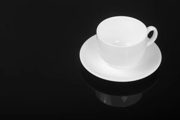 Witte cup op glanzend zwarte achtergrond — Stockfoto