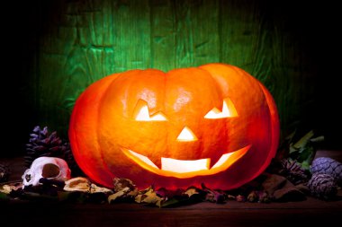 Yeşil ahşap arka plan üzerinde korkunç Cadılar Bayramı Balkabağı