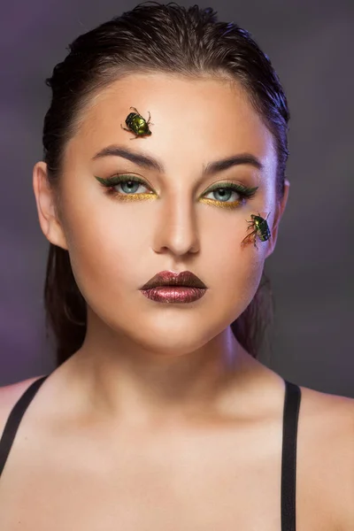 Portrait of a young woman with beetles golden bronze on her face — Stock Photo, Image