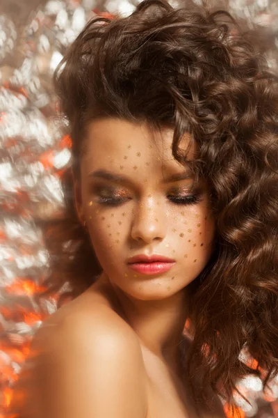 Maquillage d'hiver créatif avec des flocons de neige dorés sur son visage et coiffure ondulée — Photo