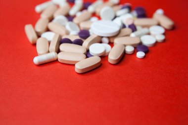 Kırmızı arka planda çeşitli haplar. Üst görünüm