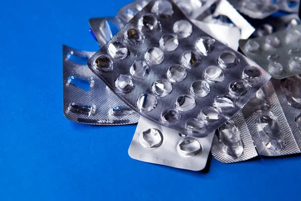 Prázdné blistry balení pilulek s jedním částečně plným balení na modrém pozadí. — Stock fotografie