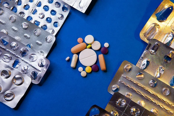 Leere gebrauchte Blisterverpackung und verschiedene Pillen auf blauem Hintergrund — Stockfoto