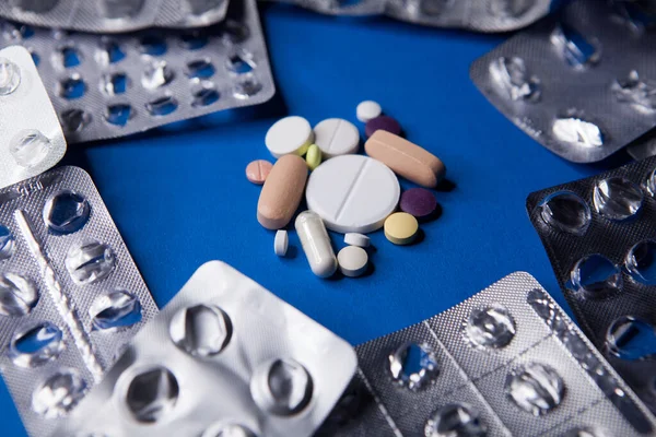Puste używane blistry i różne tabletki na niebieskim tle — Zdjęcie stockowe